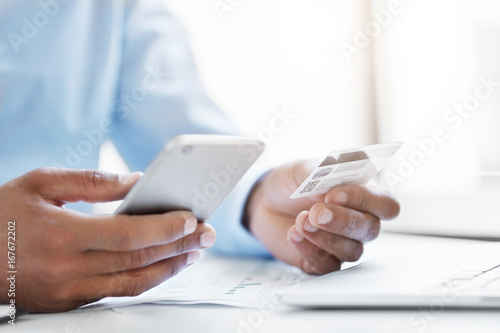 Cropped shot of businessman holding modern cell phone and credit card in hands, making transaction using mobile bank application. Businessman making orders online. People, technology and business © wayhome.studio 