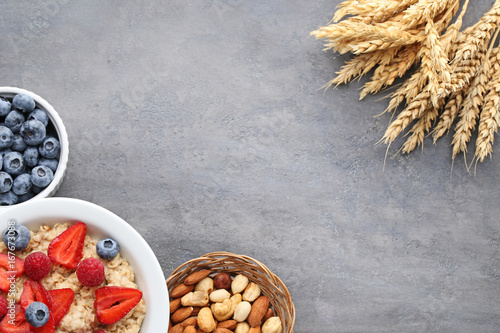 Oatmeal in plate with berries and nuts on wooden table