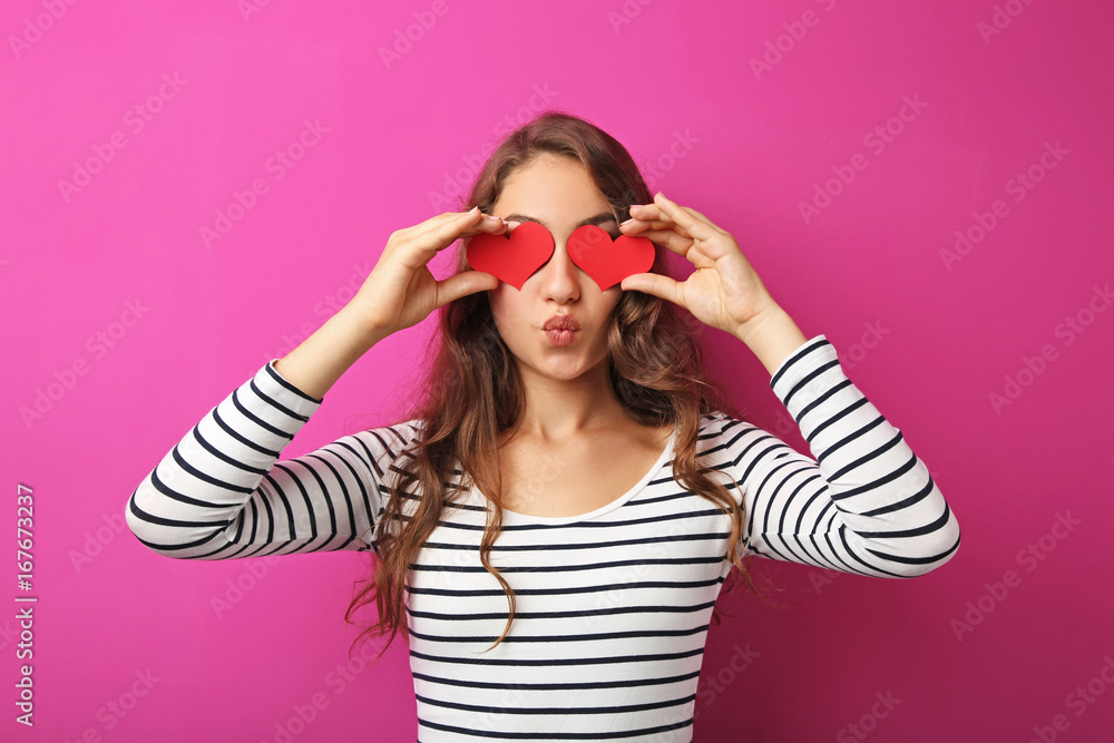 Portrait of young woman holding red hearts on pink background Portrait of young woman holding red hearts on pink background