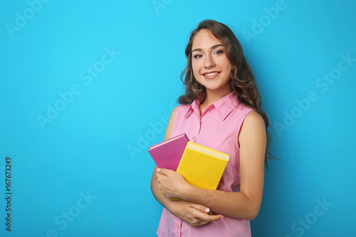 Portrait of student girl with books on blue background