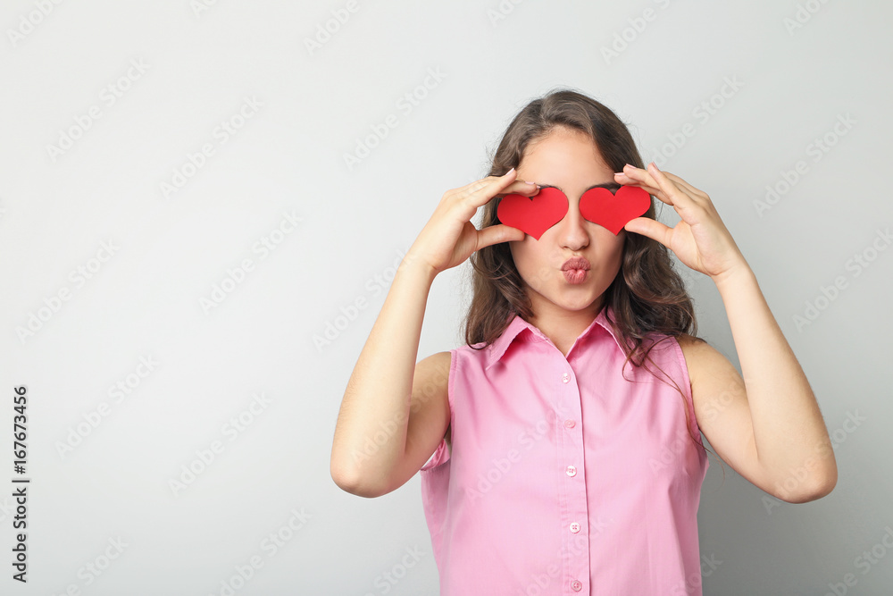 Portrait of young woman holding red heart on grey background Portrait of young woman holding red heart on grey background