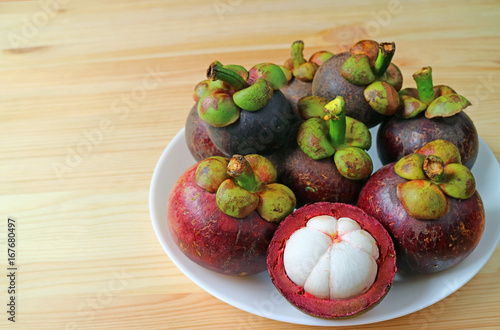 Plate of Ripe Purple Mangosteen Whole Fruits and Opened to Show Delectable Pure White Meat on the Wooden Table, with Free Space for Text and Design 
