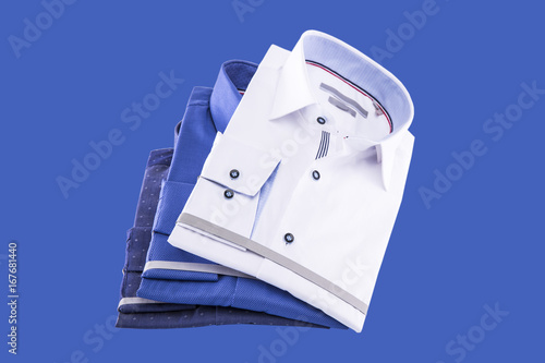 Men's shirts folded new: white, blue and bright blue on a blue background.