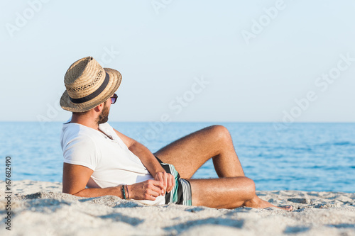 Young hipster man lying on the beach