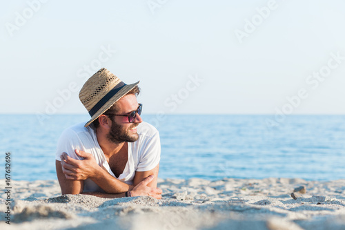 Canvas Print Young hipster man lying on the beach
