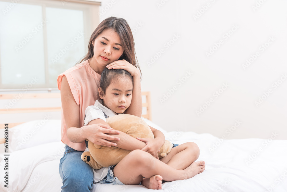 Asian mother hugging and comforting her sad daughter in bed room Asian mother hugging and comforting her sad daughter in bed room