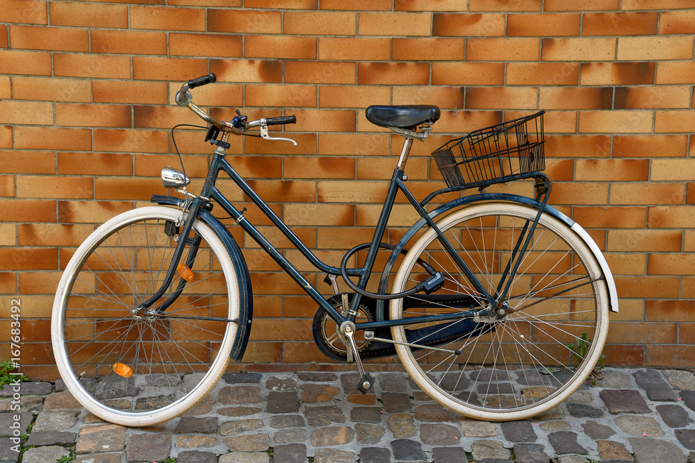 bicycle on cobblestone street leaning on brick wall