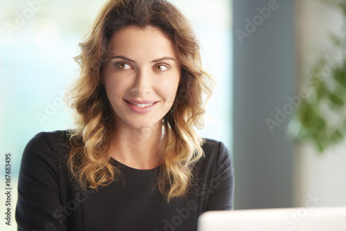 Managing her business. Shot of a young female financial advisor working on laptop at desk. 