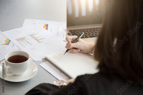 Woman hand writing notebook withcup coffee in office photo