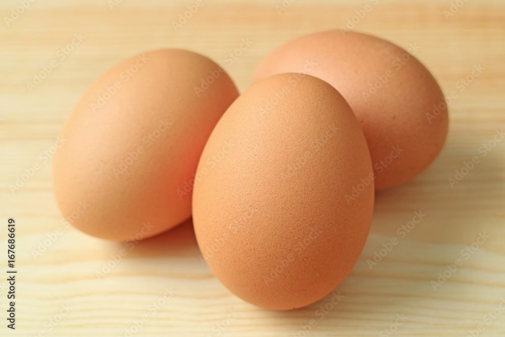 Close-up of Three fresh uncooked hen eggs on the wooden table Close-up of Three fresh uncooked hen eggs on the wooden table
