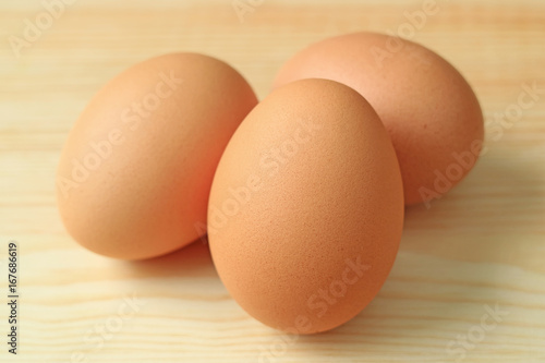Close-up of Three fresh uncooked hen eggs on the wooden table 