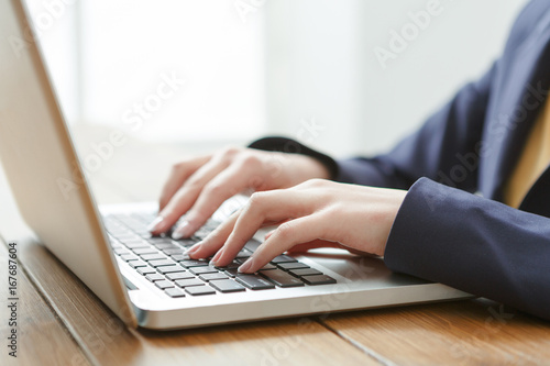 Business woman using laptop at workplace, close-up