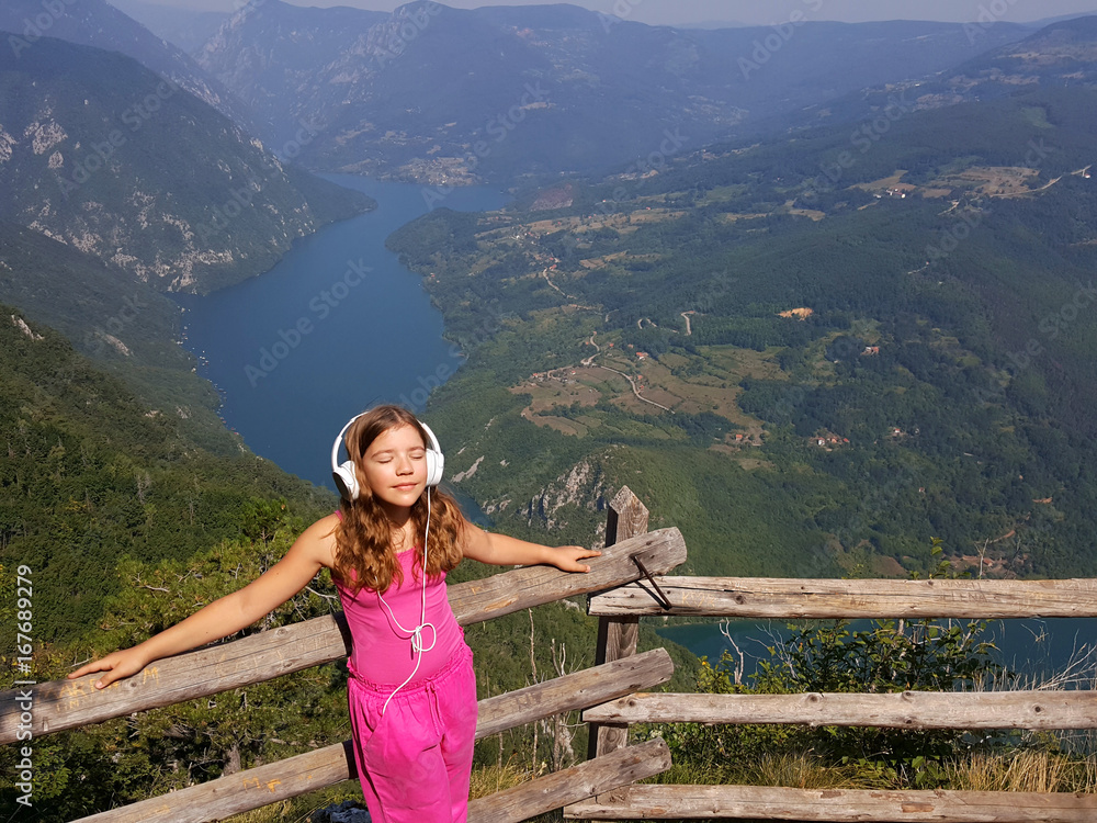 Naklejka premium little girl enjoys music at the top of the Tara mountain