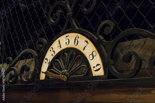 An ancient placard with figures and an iron pointer used in the elevator
