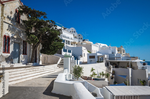 Fira, Thira town, Santorini Cyclade islands, Greece. Beautiful view of the town with white buildings, blue church's roofs and many colored flowers.