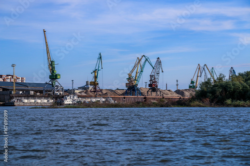 Cranes in a river port ship goods to ships. Frame made from boat
