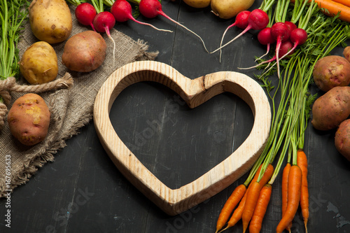 Fototapeta Naklejka Na Ścianę i Meble -  Fresh vegetables and heart on a black wooden background. Rustic style