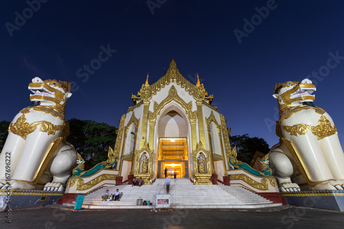Two leogryphs guarding at the Shwedagon Pagoda's western entrance in Yangon, Myanmar at night, viewed from the front. photo