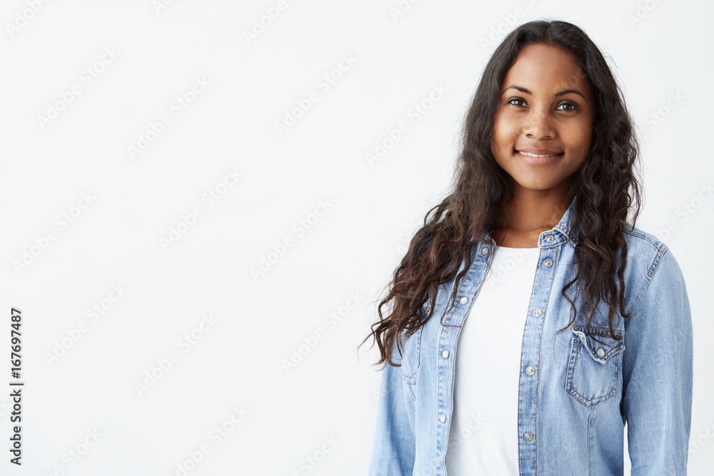 Indoor portrait of beautiful Afro-American brunette young woman smiling cheerfully, showing her white teeth to camera, feeling herself happy and carefree. Indoor portrait of beautiful Afro-American brunette young woman smiling cheerfully, showing her white teeth to camera, feeling herself happy and carefree.