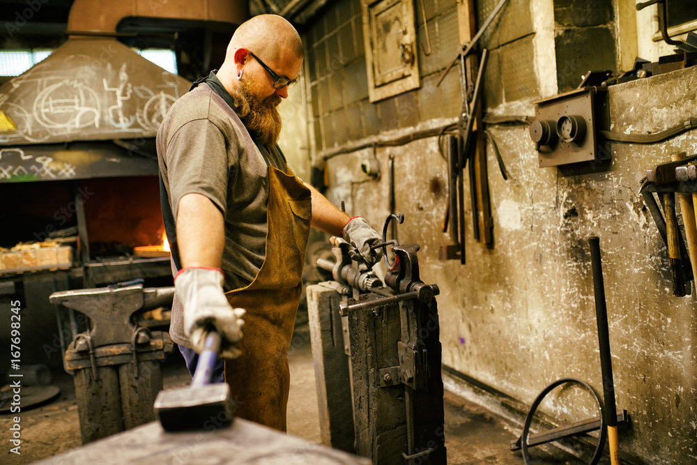 Blacksmith with beard working in his workshop Blacksmith with beard working in his workshop