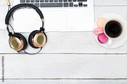 female desktop. golden headphones, coffee cup, macaroons.