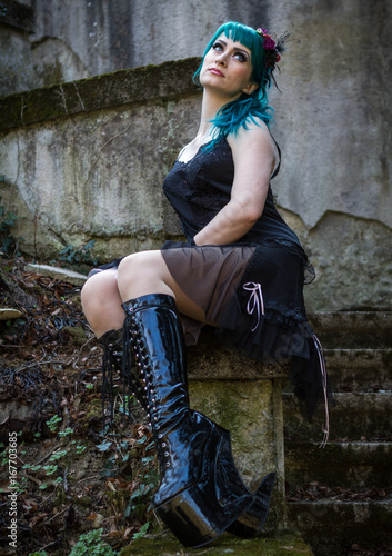 Young beautiful pin up glamour girl with green color hair, high boots on old stone vintage stairs photo