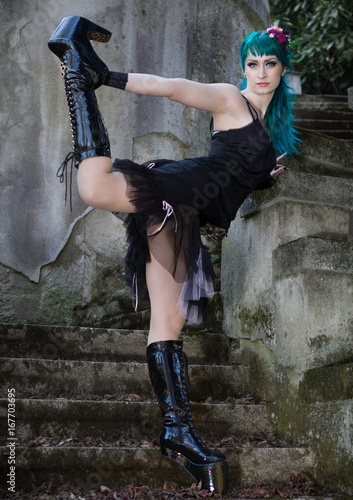 Young beautiful pin up glamour girl with green color hair, high boots on old stone vintage stairs photo