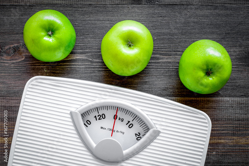 Diet for losing weight. Bathroom scale and apples on wooden background top view