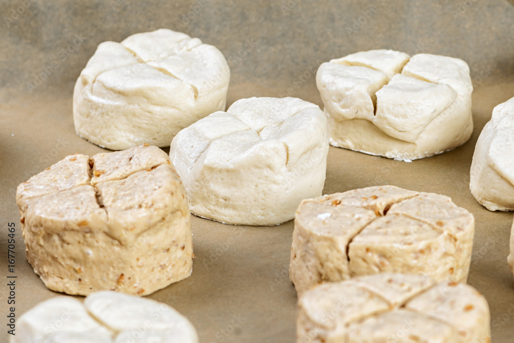 unbaked bread rolls on backing paper unbaked bread rolls on backing paper