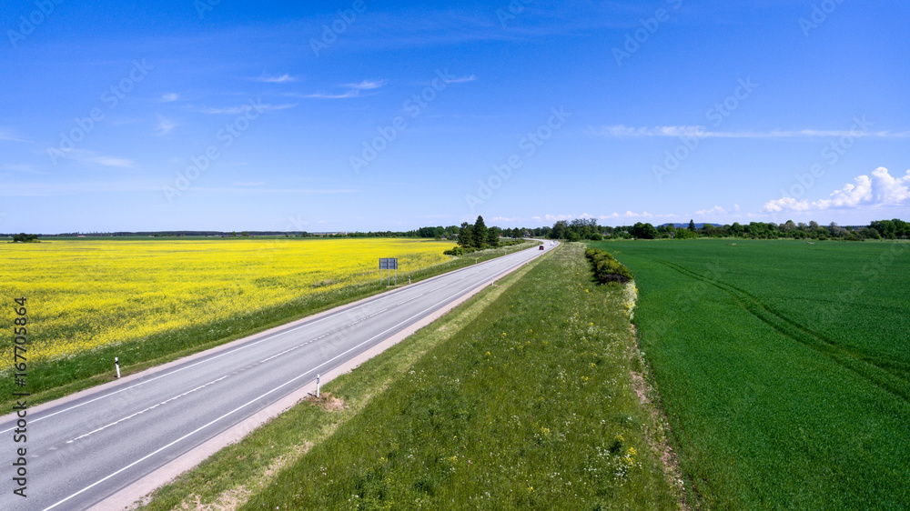 Above view over yellow raps fields and the European E20 route. Expressway from Narva to Tallinn in Estonia, Europe Above view over yellow raps fields and the European E20 route. Expressway from Narva to Tallinn in Estonia, Europe