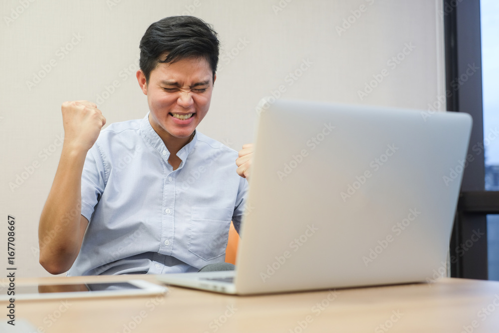 close up asian man feeling extremely happy with laptop computer at office room close up asian man feeling extremely happy with laptop computer at office room