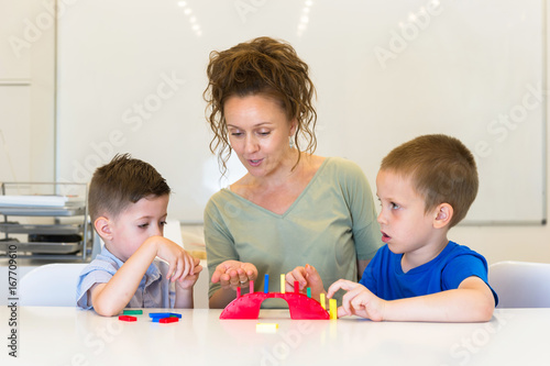 teacher woman play with two child boy domino in classroom