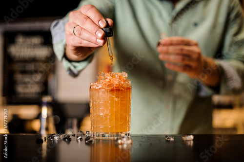 Bartender adds bitter to cocktail