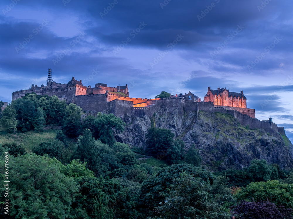 View of Edinburgh Castle looming over the beautiful city of Edinburgh at night.