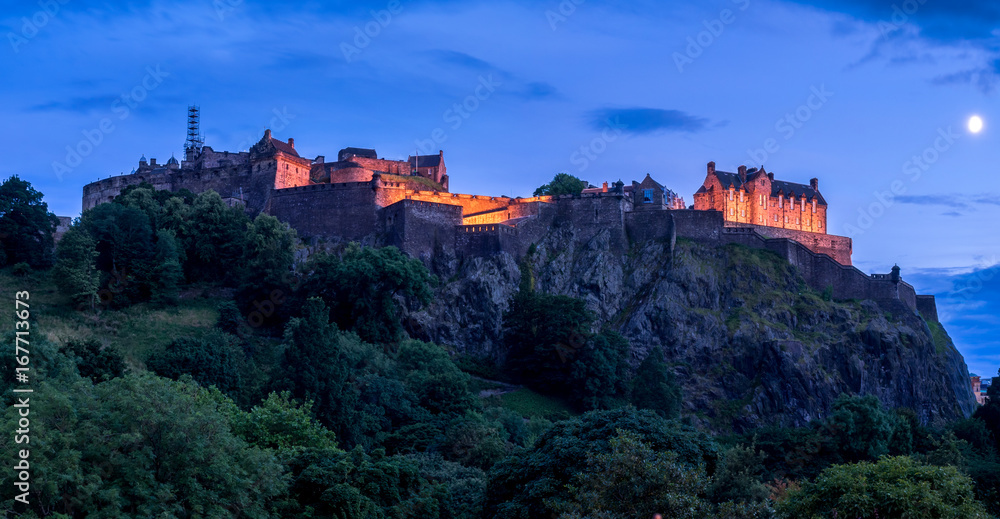 View of Edinburgh Castle looming over the beautiful city of Edinburgh at night.