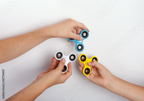 Three hands showing fidget spinners in different colors