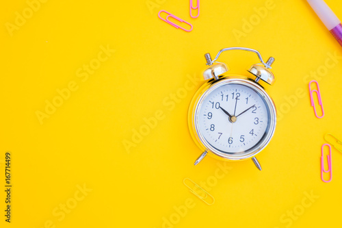 back to school or office styed scene with alarm clock and copy space on yellow background