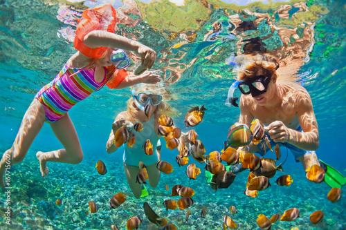 Happy family - father, mother, child in snorkeling mask dive underwater with tropical fishes in coral reef sea pool. Travel lifestyle, water sport adventure, swimming on summer beach holiday with kids