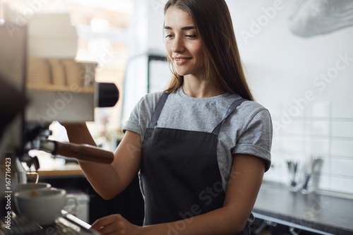 Tableau sur toile Female student on her summer job serving coffee working as a barista in a local