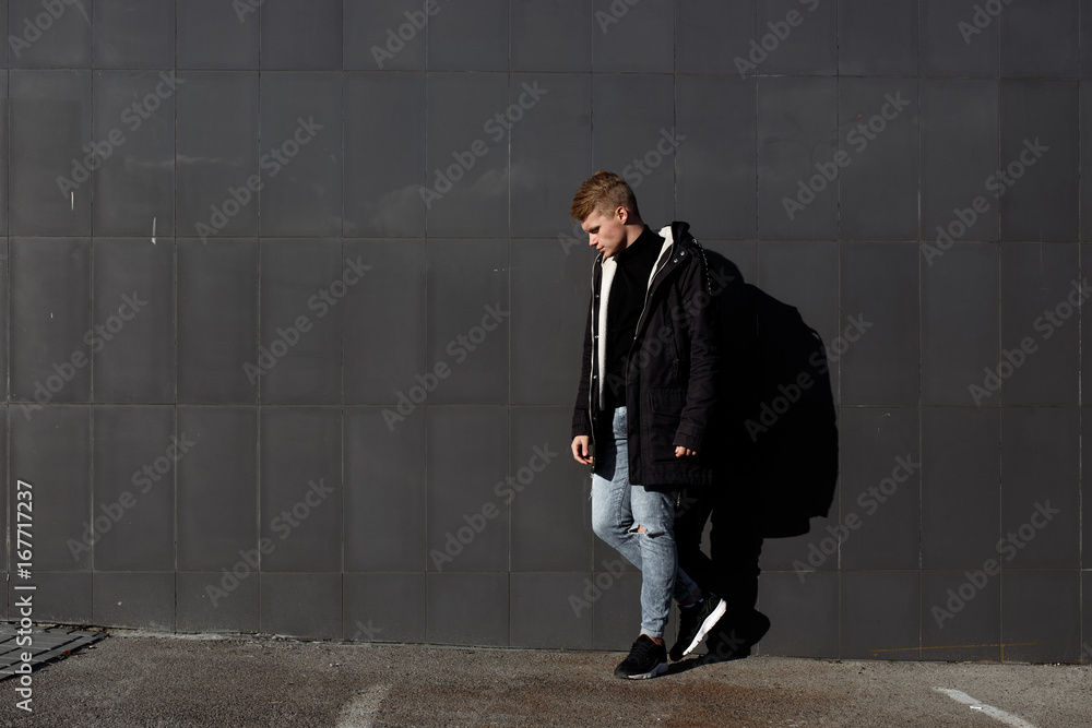 Obraz premium Young stylish redhead man in trendy outfit posing against urban background