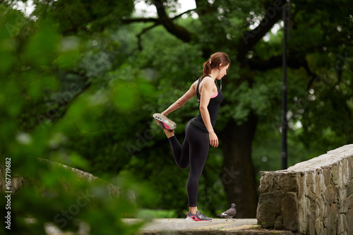 Sportswoman stretching in summer park