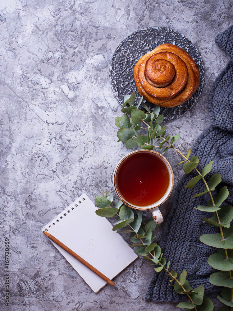Feminine workspace with bun, cup of tea and notebook Feminine workspace with bun, cup of tea and notebook