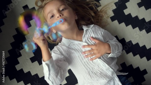 Top view of a cute little girl blowing soap bubbles