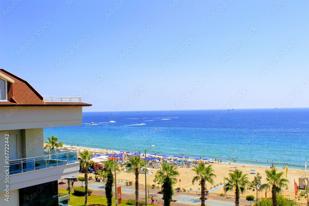 Fototapeta premium View of the embankment of the city of Alanya and Cleopatra Beach: the sea, sand, palm trees, sun beds and beach umbrellas.