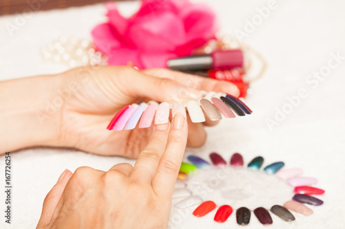 Hands of a woman who chooses the color of her nail polish