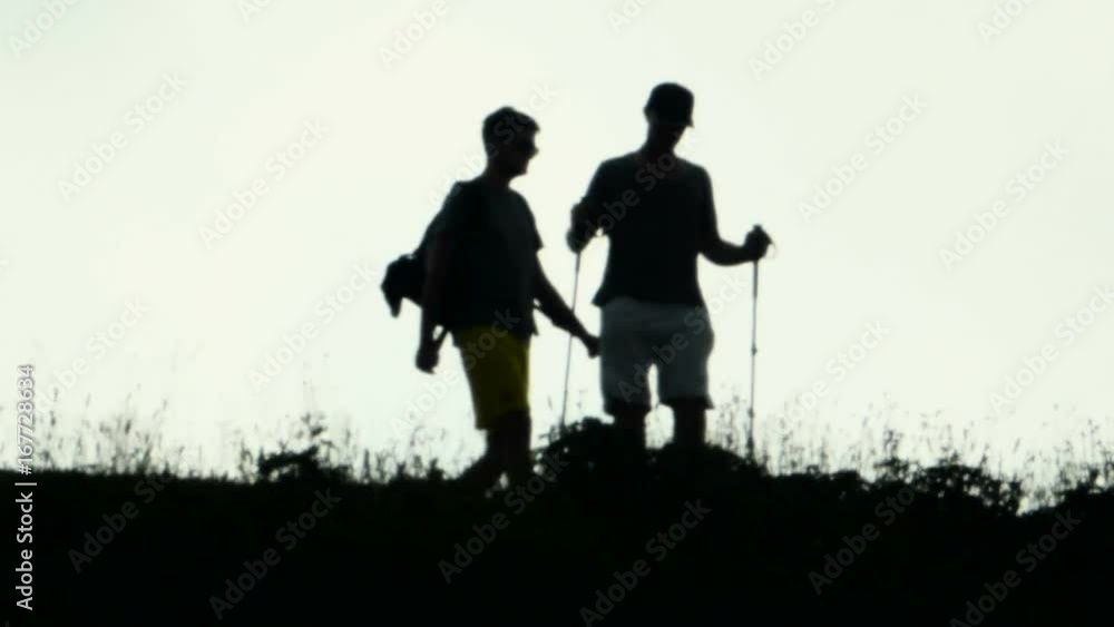 Silhouettes of three male trekkers in the mountains during sunset Silhouettes of three male trekkers in the mountains during sunset