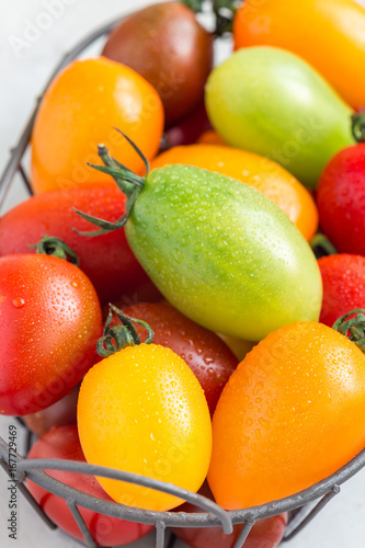 Small colorful cherry tomatoes in metal basket  horizontal  closeup