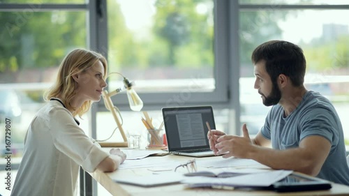 Serious millennial guy helping female groupmate with home assignment