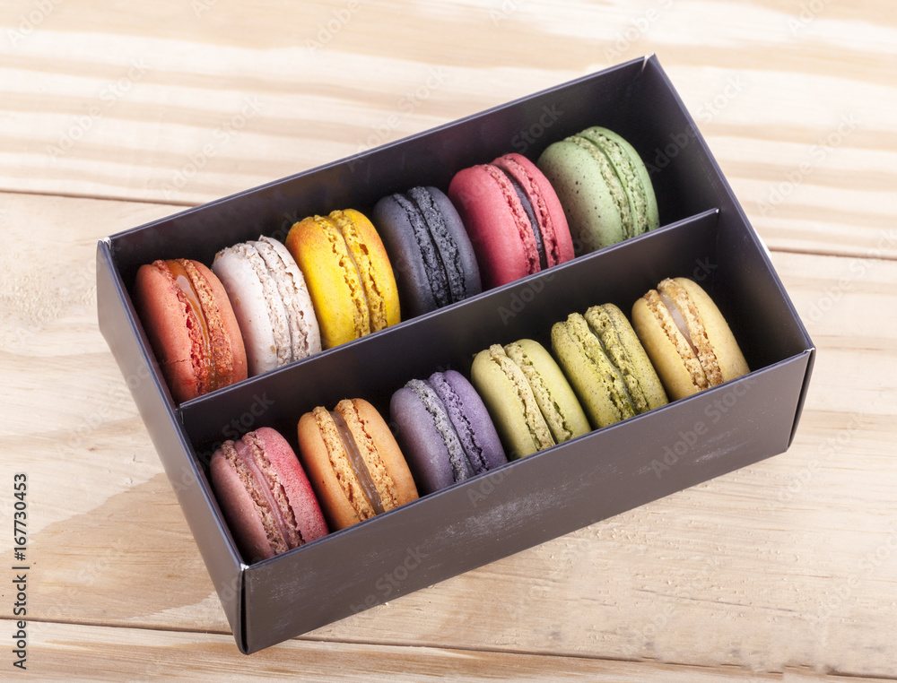Colorful macaroons in a gift box and marshmallow in coffee cup on wooden table. Colorful macaroons in a gift box and marshmallow in coffee cup on wooden table.
