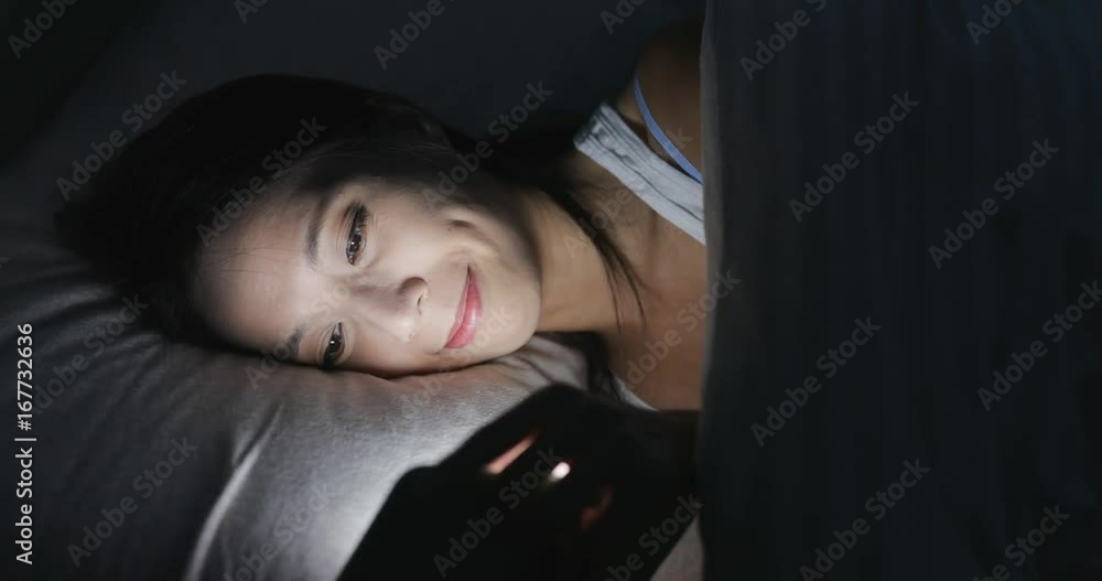 Woman use of cellphone on bed at night Woman use of cellphone on bed at night